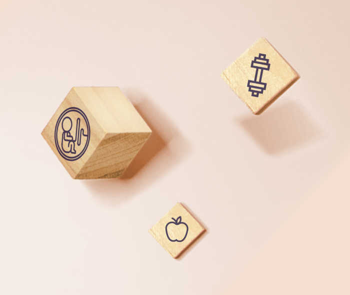 Ein Holzwürfel mit einem Kindersymbol und zwei Holzplättchen mit Symbolen für Sport und Ernährung